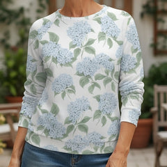 Woman wearing a floral-patterned shirt and denim shorts standing outdoors.