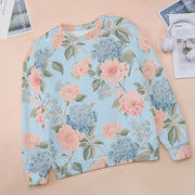 Floral patterned sweatshirt on a beige surface with magazines and headphones.