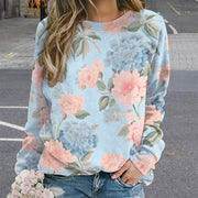 Person wearing a floral sweatshirt with pink flowers on a light blue background.