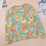 Colorful pumpkin patterned sweatshirt on a light pink surface with magazines and headphones.